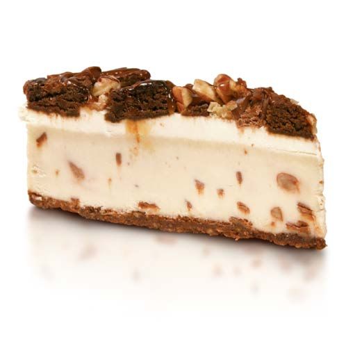 A slice of cheesecake with nuts on top on a white surface.