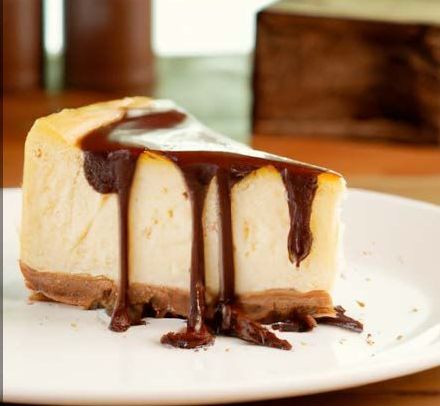 A slice of cheesecake with chocolate sauce on a white plate