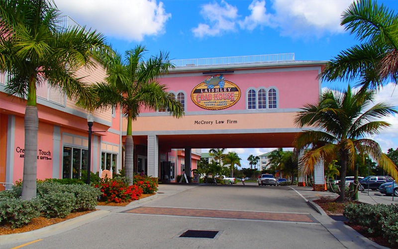 Pink building with arched entrance, palm trees, blue sky.