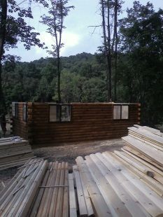 A log cabin is being built in the middle of a forest.