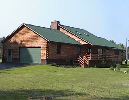 A large log cabin with a green garage door