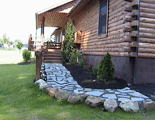 A log cabin with a stone walkway leading to the porch