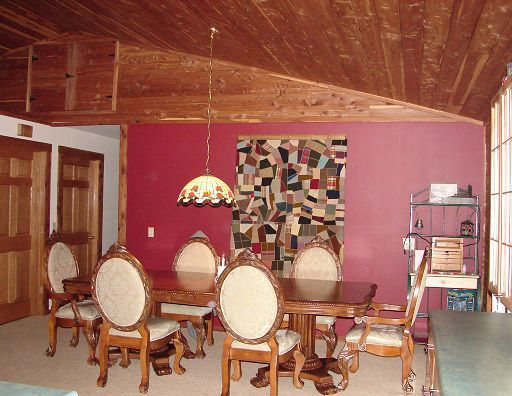 A dining room with a table and chairs and a lamp hanging from the ceiling