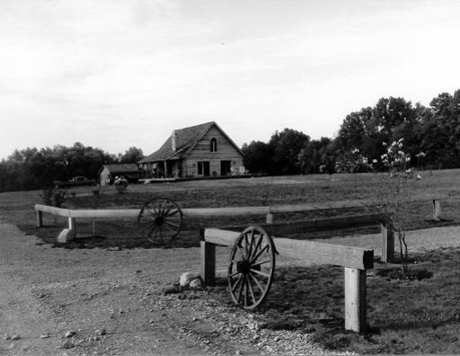A black and white photo of a farm with a house in the background