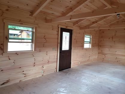 A wooden room with a door and two windows.