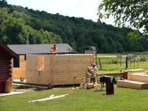 A group of people are building a log cabin in a field.