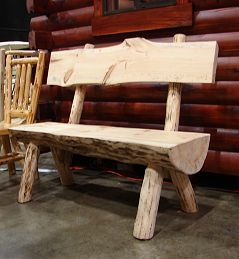 A wooden bench is sitting in front of a log cabin.