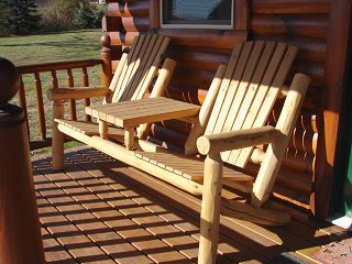 Two wooden chairs on a porch next to a log cabin