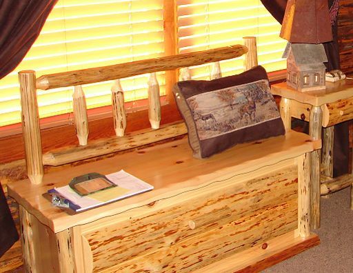 A wooden bench with two pillows and a lamp on it
