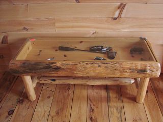 A wooden coffee table with a glass top is sitting on a wooden floor.