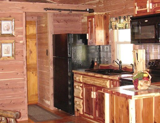 A kitchen with wooden cabinets and a black refrigerator
