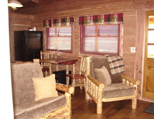 A living room in a log cabin with two chairs and a table