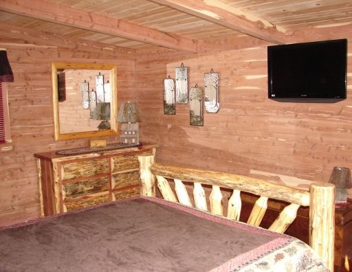 A bedroom with a bed , dresser , mirror and television.