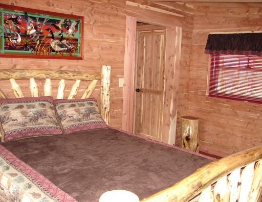 A bedroom in a log cabin with a bed and a window