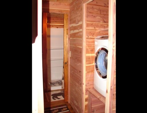 A washer and dryer are built into a wooden wall.