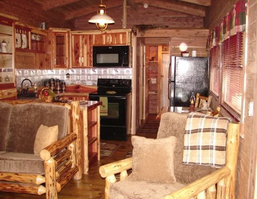 A living room with wooden furniture and a kitchen in the background