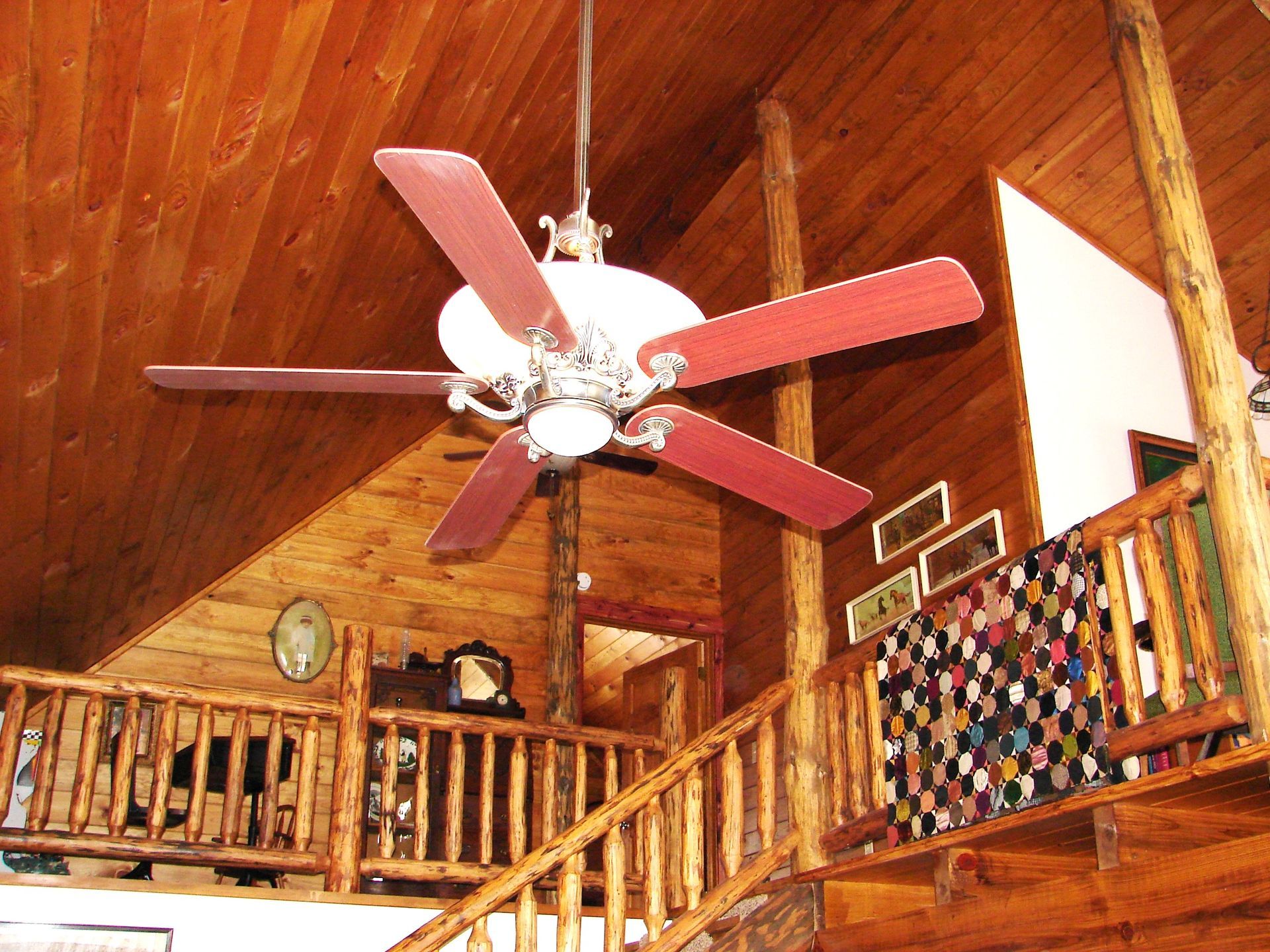 A wooden staircase with a ceiling fan above it