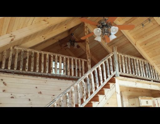 A wooden staircase leading to a loft with a ceiling fan