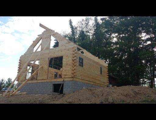 A log cabin is being built on top of a dirt hill