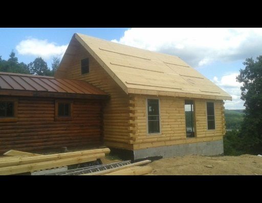 A log cabin with a metal roof is being built