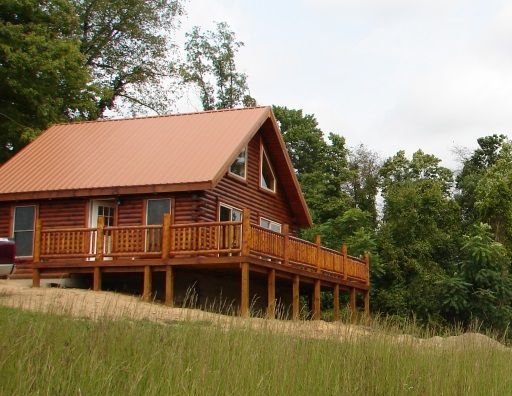 A log cabin with a red roof and a large deck