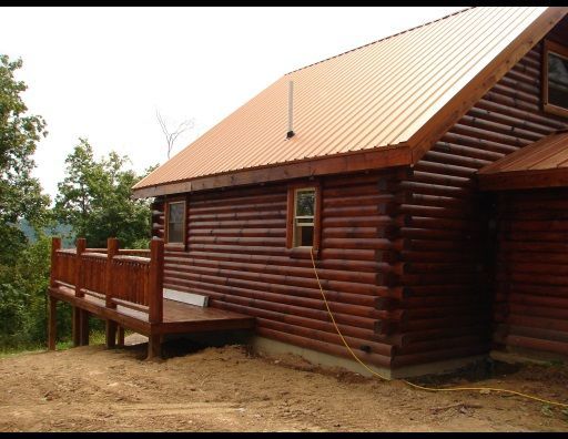 A log cabin with a metal roof and a wooden deck