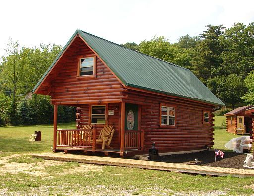 A small log cabin with a green roof