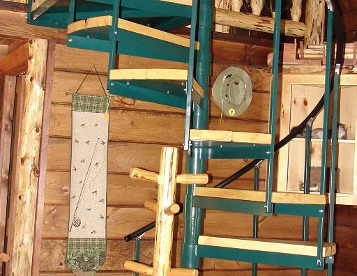 A spiral staircase in a log cabin with a clock on the wall