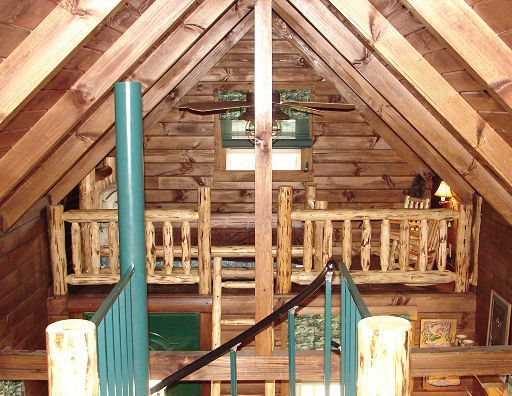 The inside of a log cabin with a staircase leading up to the second floor