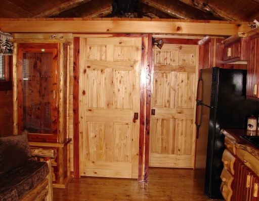 A kitchen in a log cabin with a black refrigerator