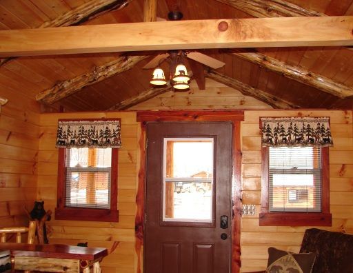 A living room in a log cabin with a ceiling fan