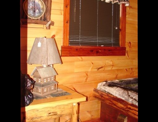 A lamp sits on a wooden table next to a window
