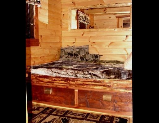 A bed in a wooden cabin with drawers underneath it