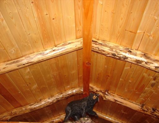 A black bear statue is sitting in the corner of a wooden room.