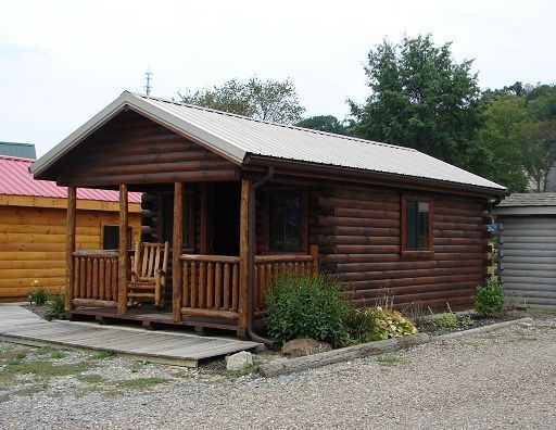 A small log cabin with a porch and a rocking chair