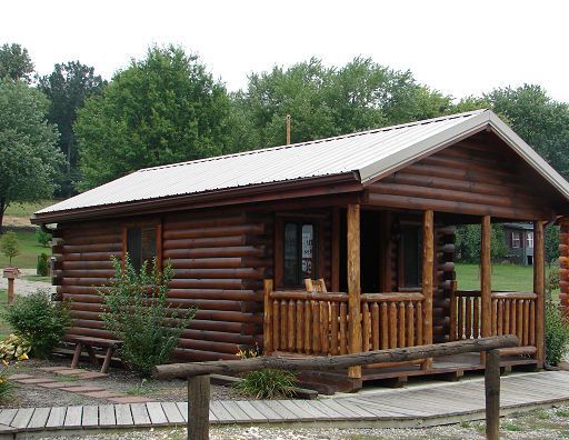 A small log cabin with a porch and a metal roof