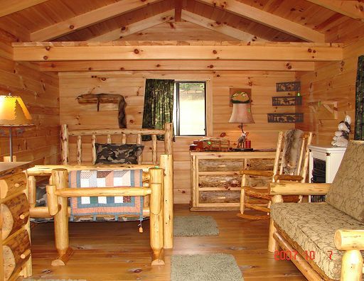 A wooden cabin with two beds and a rocking chair
