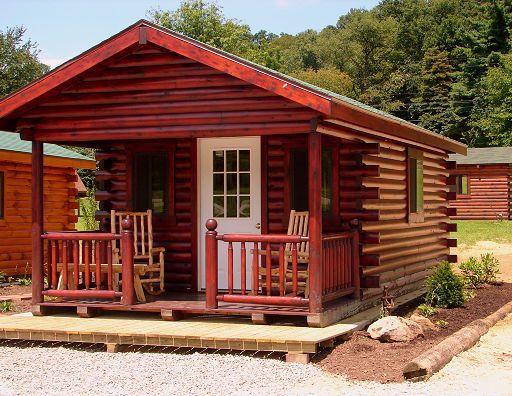 A small log cabin with a porch and rocking chairs