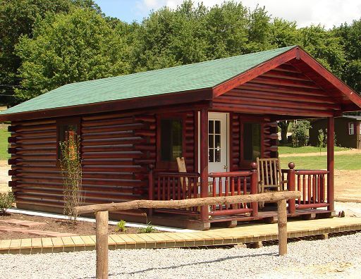 A small log cabin with a green roof and a porch