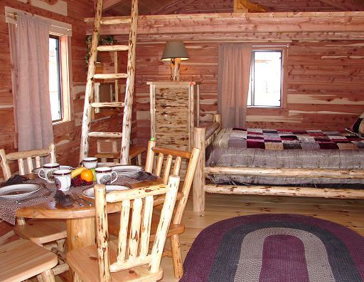 A wooden cabin with a table and chairs and a bed
