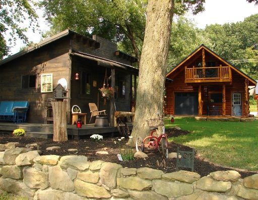 A small house with a porch next to a large house