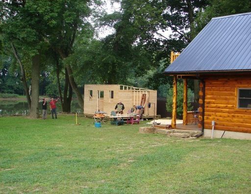 A log cabin is being built in a grassy field