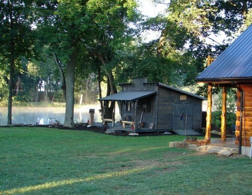 A log cabin sits in the middle of a lush green field
