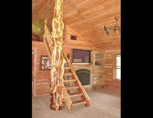 A wooden staircase leading up to a fireplace in a log cabin.