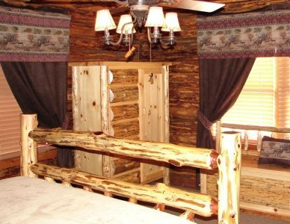 A bedroom in a log cabin with a bed and a chandelier