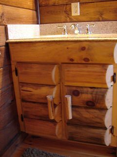 A bathroom vanity made of logs with a sink and faucet.