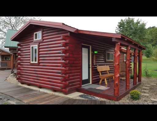 A small log cabin with a porch and a bench