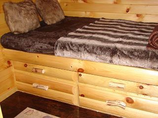 A wooden bed with drawers underneath it in a cabin.
