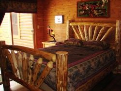 A bed made of logs in a cabin with a sliding glass door.