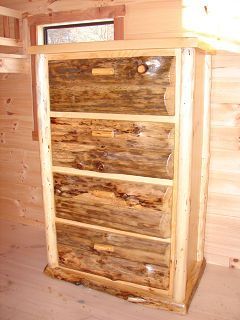 A wooden chest of drawers is sitting in a wooden room next to a window.